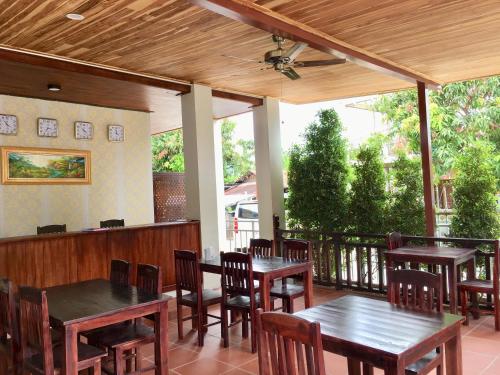 un patio con mesas y sillas y un ventilador de techo. en Le KhounSok Boutique Hotel, en Luang Prabang