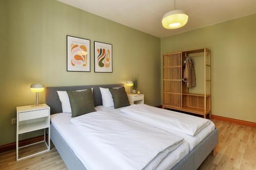 1 dormitorio con 1 cama blanca grande y 2 lámparas en Central, modern city apartments - by homekeepers, en Würzburg