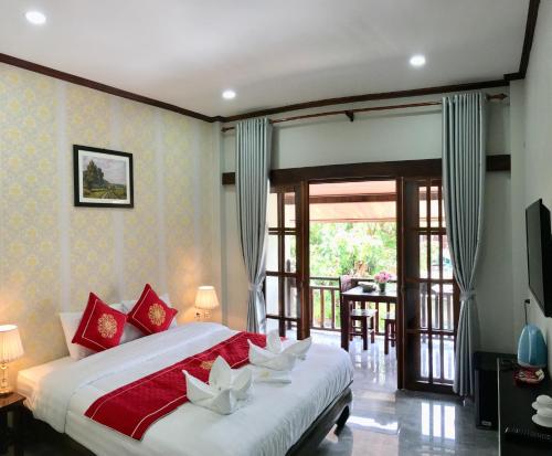 1 dormitorio con 1 cama grande con almohadas rojas y blancas en Le KhounSok Boutique Hotel, en Luang Prabang