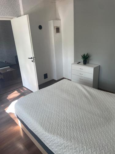 a white bedroom with a bed and a dresser at Soelaane 12 Apartment2 in MikitamÃ¤e