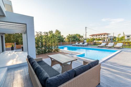 a patio with a table and chairs next to a swimming pool at Assos Luxury Villas in Pefkochori