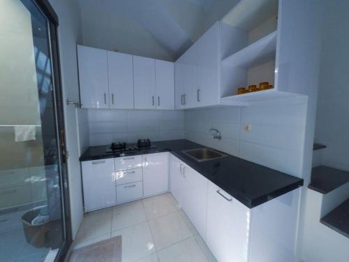 una cocina blanca con armarios blancos y fregadero en Sukasari Guesthouse, en Tasikmalaya