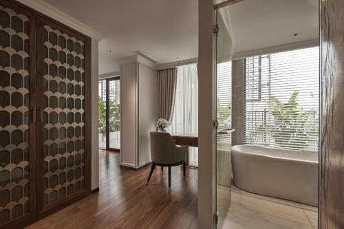 a bathroom with a tub and a desk with a chair at La Siesta Premium Saigon in Ho Chi Minh City