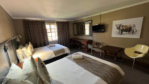 a hotel room with two beds and a desk at Mountainview Inn in Harrismith