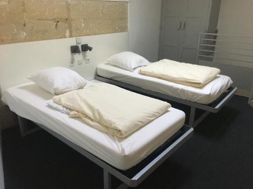 two beds in a hospital room with white sheets and pillows at Ethic étapes le Cart in Sommières