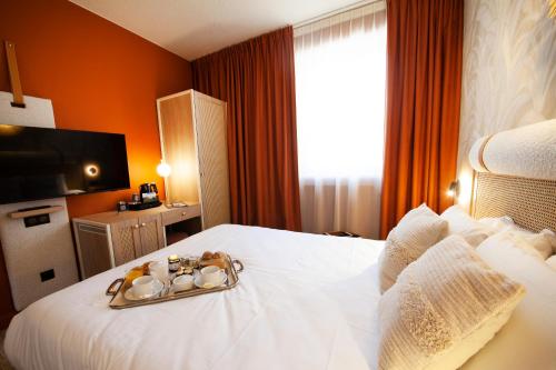 a hotel room with a white bed with a tray of towels at Kyriad Prestige Hotel Clermont-Ferrand in Clermont-Ferrand