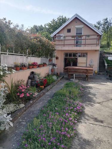 a house with a bench in a garden with flowers at KOD BAKE in Vrdnik