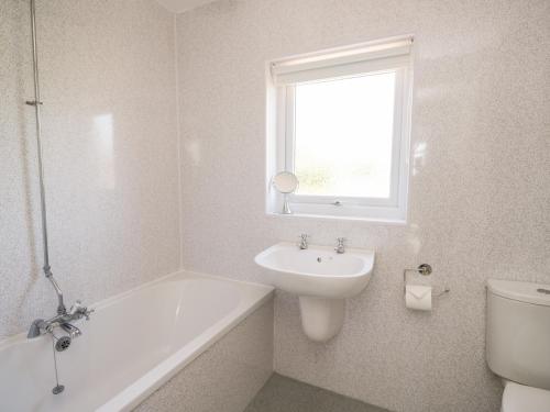 a bathroom with a sink and a tub and a toilet at Pow-Wow Shore Cottage in Annan
