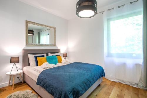 een slaapkamer met een bed met een spiegel en een raam bij Panorama Blue Apart Invest in Szklarska Poręba