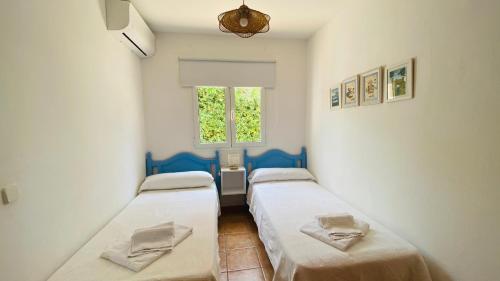 two beds in a small room with a window at Villa Áncora in Binibeca
