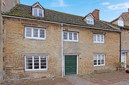 an old brick house with a green door at Cotswold Cottage- Central Witney in Witney