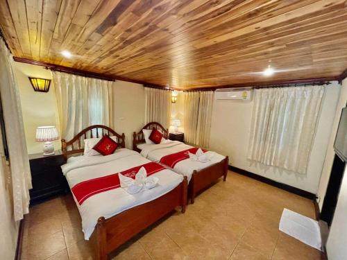 a bedroom with two beds with red pillows at Villa Phathana Royal View Hotel in Luang Prabang