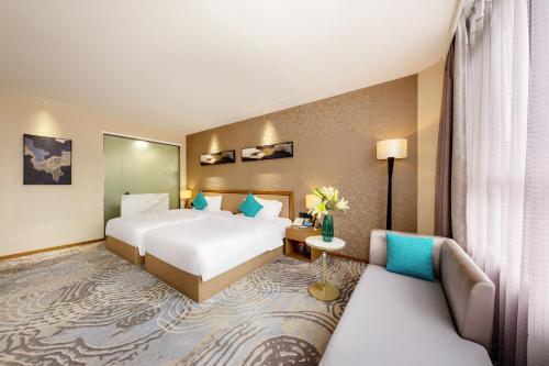 a hotel room with two beds and a couch at Qianhai Holiday Hotel in Bao'an