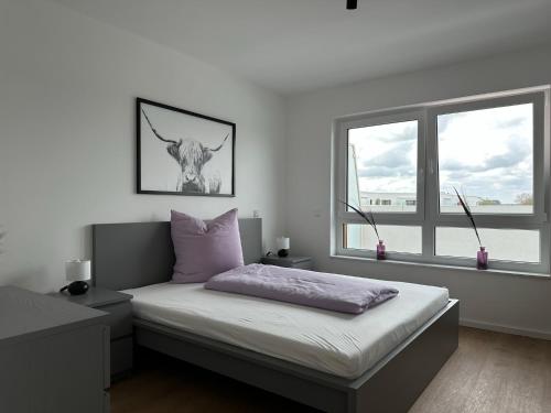 ein Schlafzimmer mit einem Bett und zwei Fenstern in der Unterkunft Ostwall Terrassen Apartment 5.29 in Bocholt