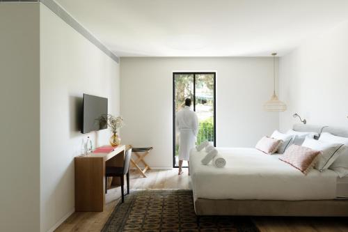 a white bedroom with a bed and a desk at THE Y HOUSE in Jerusalem