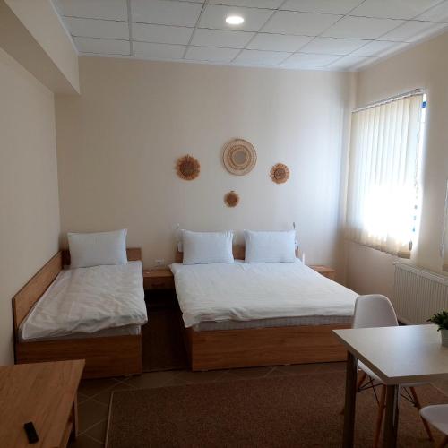 Cette chambre comprend 2 lits et une table. dans l'établissement Fermelor Residence, à Piatra Neamţ