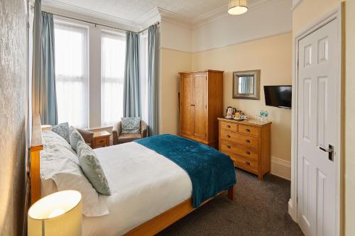 a bedroom with a bed and a chair and a television at The Tennyson in Bridlington