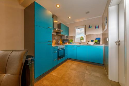 a kitchen with blue cabinets and a sink at Premiumferienhäuser Agena - Ankaa in Hasselfelde