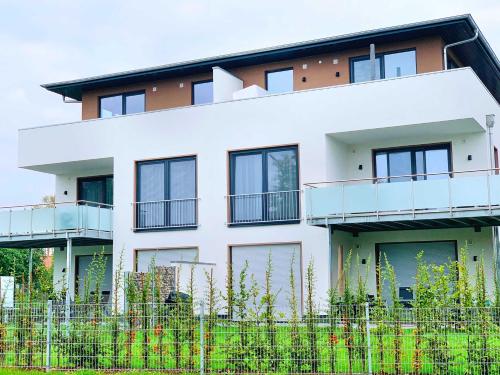 a white building with a fence in front of it at Luxus_SPA_OG_Fewo DREAMTIME _WE 3_ in Göhren-Lebbin