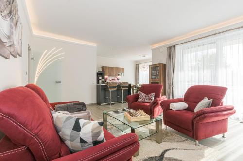 a living room with two red chairs and a table at Luxus_SPA_OG_Fewo DREAMTIME _WE 3_ in Göhren-Lebbin