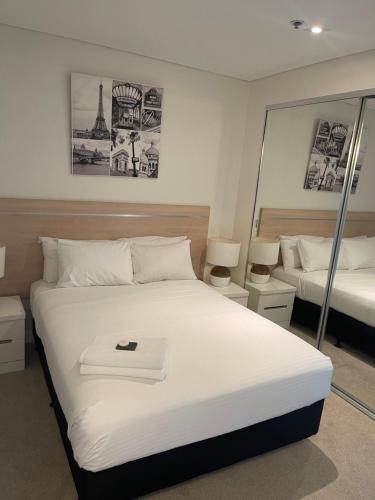 um quarto com uma grande cama branca e um espelho em 2br ANTEA Embassy free parking em Adelaide