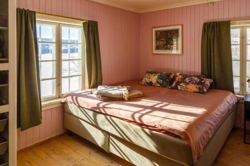 a bedroom with a bed with pink walls and windows at Vinjestogo- mesmerizing mountain view, sauna with a view and eco living in an old school house in Løken