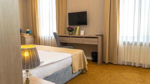 a hotel room with a bed and a desk with a television at Grand Midway Hotel in Baku