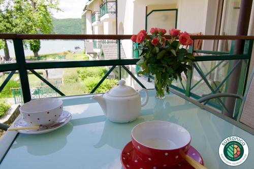 a table with two cups and a vase with roses at La Baie des Voiles, FEET IN THE CRYSTAL WATERS, 12 Apts from studio to Duplex, LLA Selections by Location lac Annecy in Duingt