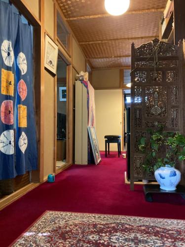 a hallway with red carpet and a room with a table at ＯＫＵＮＯ ＩＥ in Oshima
