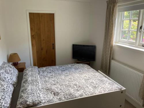 a bedroom with a bed and a flat screen tv at Ashdown Forest character cottage, 18th Century in Crowborough