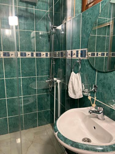 een groene betegelde badkamer met een wastafel en een spiegel bij House Inn in Pirot