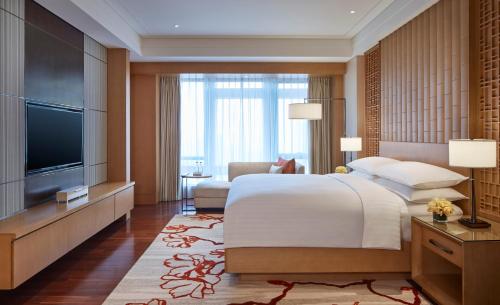 a bedroom with a large bed and a flat screen tv at Zhuhai Marriott Hotel in Zhuhai