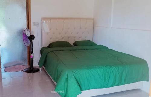 uma cama com um edredão verde num quarto em Senaru Garden Homestay em Senaru