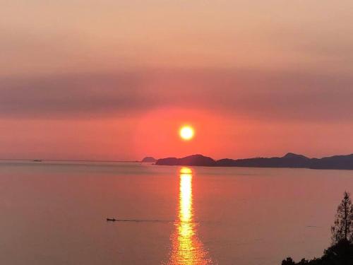 a sunset over a body of water with a boat at Cliff top Terrace in Kuranomoto
