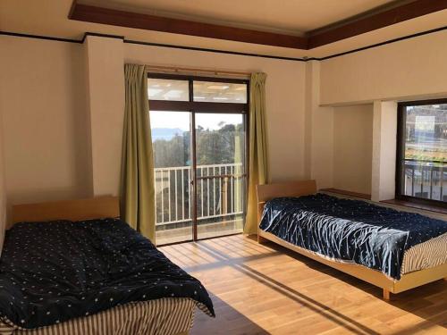 a bedroom with two beds and a large window at Cliff top Terrace in Kuranomoto