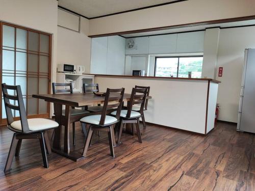Una habitación con una mesa y sillas y una cocina. en Cliff top Terrace, en Kuranomoto