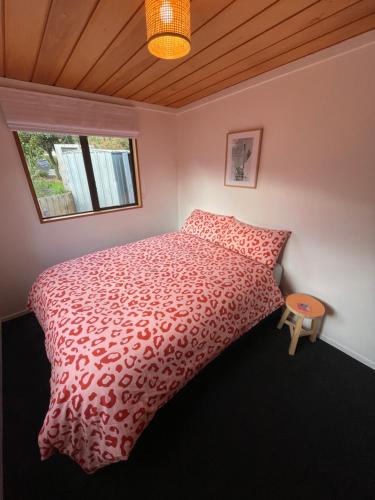 a bedroom with a bed with a red comforter and a window at Ski Pad Methven in Methven
