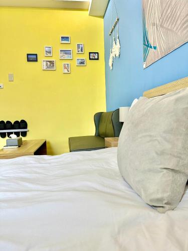 a bedroom with a white bed and a yellow wall at 莫蘭狄 in Taichung