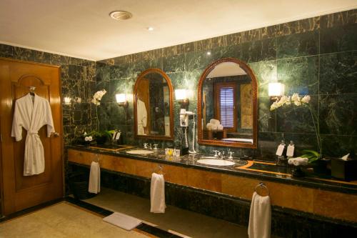 ein Badezimmer mit zwei Waschbecken und einem großen Spiegel in der Unterkunft The Royal Beach Seminyak Bali in Seminyak