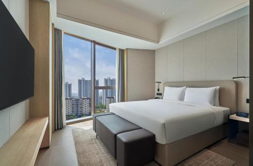 a bedroom with a large bed and a large window at Hyatt Place Yantai Development Zone in Yantai