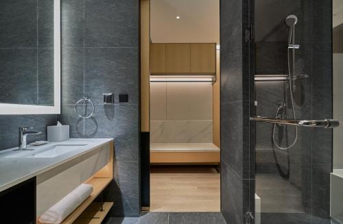 a bathroom with a shower and a sink and a tub at Hyatt Place Yantai Development Zone in Yantai