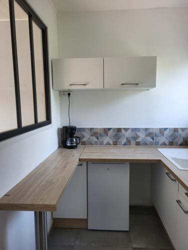 une cuisine avec des armoires blanches et un comptoir en bois dans l'établissement Studio proche gare TGV Haute Picardie, à Dompierre-Becquincourt