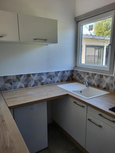 a kitchen with a sink and a window at Studio proche gare TGV Haute Picardie in Dompierre-Becquincourt