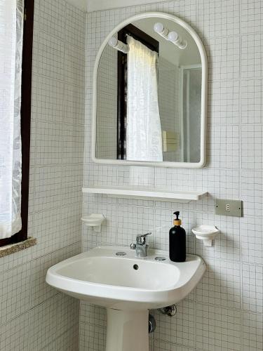 a white bathroom with a sink and a mirror at Oleandro, Rena Majore in Rena Majore