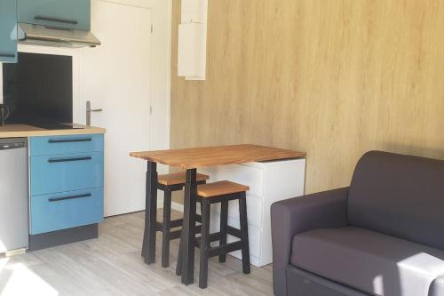 a kitchen with a table and a couch in a room at Studio de jardin au calme in Hennebont