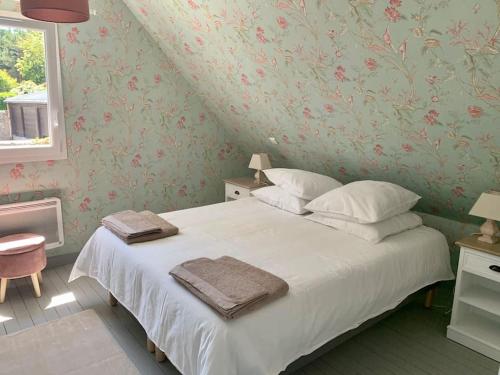 1 dormitorio con 1 cama con sábanas blancas y papel pintado con motivos florales en Maison Bord de Mer dans la Petite Irlande, en Auderville