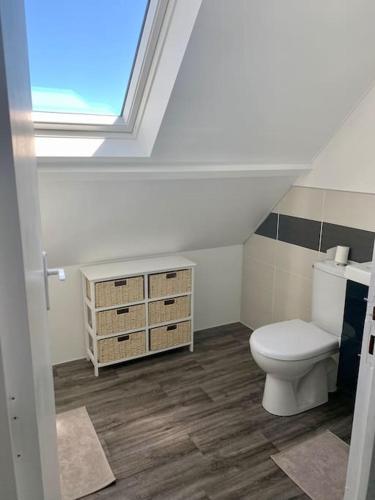 une salle de bain avec des toilettes blanches et une fenêtre dans l'établissement Maison Bord de Mer dans la Petite Irlande, à Auderville