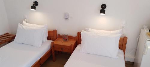 two beds in a room with white sheets and pillows at Loggia in Agia Galini