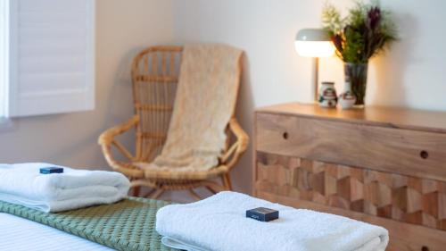 a room with a chair and towels on a bed at Halcyon in Kiama
