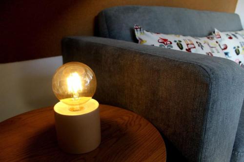 a light on a table next to a couch at Reload Apartment in Miskolc